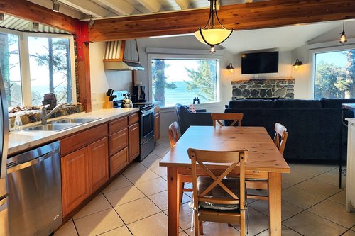 Large windows with views of the ocean and the forest.